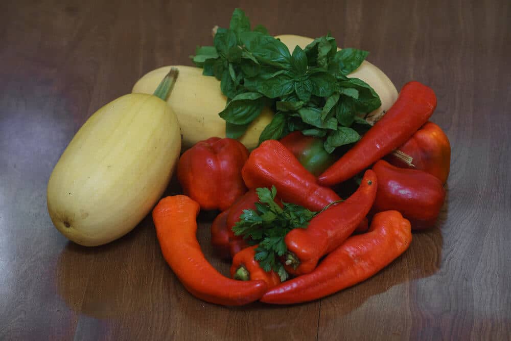 Peppers, squash, cilantro, and basil on a table