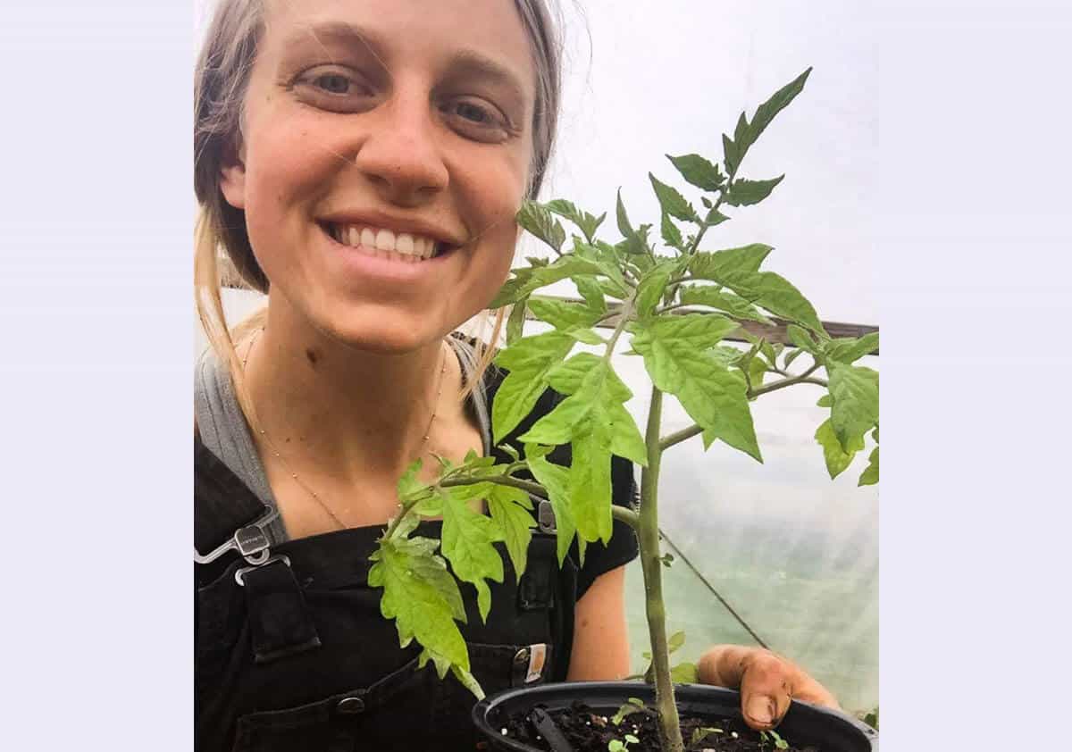 Woman smiling and holding a tomato plant