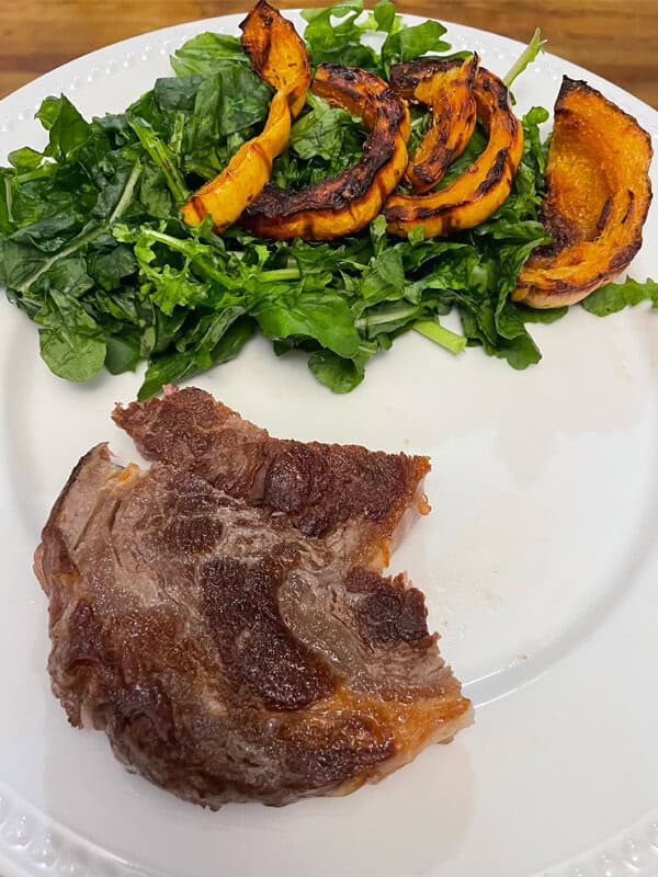 Steak and squash on a white plate