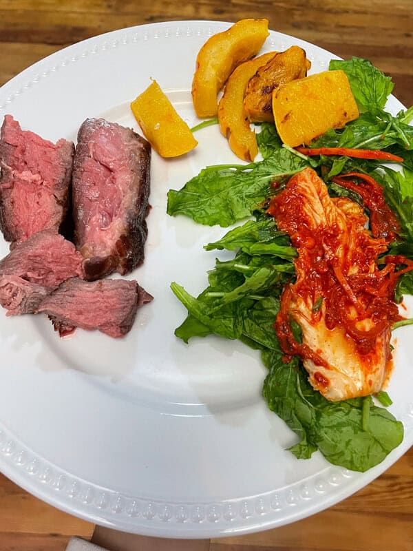 Oven Baked Chuck Roast sliced and on a plate with a salad and veggies